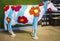Cow decorated with yellow red orange magenta flower and cyan strips in a store