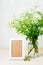 Cow parsley flowers in a glass jar and an empty picture frame