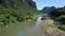 Cow stands on sandy reach of river meandering in valley