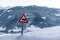 Cow warning traffic sign european red triangle. Snow-covered meadow and mountains, sunset at the background.