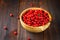 Cowberry, foxberry, cranberry, lingonberry in a wooden bowl on a brown wooden table.