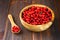 Cowberry, foxberry, cranberry, lingonberry in a wooden bowl on a brown wooden table.