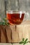 Cowberry herbal leaf tea  in a glass cup with red bilberry leaves nearby on rustic wood