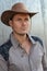 Cowboy couture. Portrait of young man wearing cowboy hat while standing against gray wall background