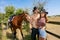 Cowboy and cowgirl couple with horse and saddle argue with ranch in background