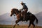 Cowboy on his horse walking through dust in the desert