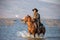 Cowboy on his horse walking through dust in the lake