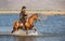 Cowboy on his horse walking through dust in the lake