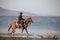 Cowboy on his horse walking through dust in the lake