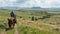 Cowboy on horseback exploring scenic hills and open fields