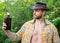 cowboy man showing whiskey bottle. cowboy man with whiskey outdoor. photo of cowboy man