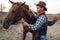 Cowboy poses with horse on texas ranch, wild west