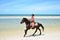 Cowboy is riding Horse walk on the beach