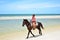 Cowboy is riding Horse walk on the beach