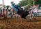 A cowboy is thrown from a bucking bull