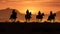 Cowboys, on horseback, silhouetted by the setting sun