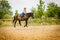 Cowgirl doing horse riding on countryside meadow