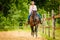 Cowgirl doing horse riding on countryside meadow