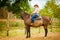 Cowgirl doing horse riding on countryside meadow