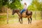 Cowgirl doing horse riding on countryside meadow