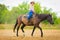 Cowgirl doing horse riding on countryside meadow