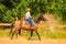 Cowgirl doing horse riding on countryside meadow