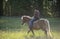 Cowgirl horseback riding in forest