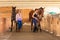 Cowgirl and jockey walking with horses in stable