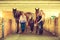 Cowgirl and jockey walking with horses in stable