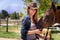 Cowgirl, portrait and happy woman with horse at farm outdoor in summer or nature in Texas for recreation. Western hat