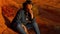 Cowgirl relaxing on a red rock in the desert of Arizona