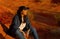 Cowgirl relaxing on a red rock in the desert of Arizona