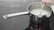 The cows milk boils in a saucepan. Woman stirs milk in saucepan