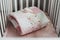 Cozy baby cot with pink patchwork blanket.  Bedding and textile for children nursery. Nap and sleep time