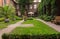 Cozy backyard in old european house. Calm empty yard with bench, sculpture, lawn and outdoor umbrella. Big peaceful patio.