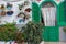 Cozy backyard with white wall, green entrance with curtain and bright flowers in pots. Rustic yard decoration.