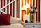 Cozy bedroom close-up in dark red tones and with romantic details: candles, roses bouquet, bedside lights