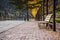 A cozy bench in the park, people are walking along the path.