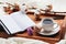 Cozy breakfast with cup of coffee, cotton flower, macaroon and open notebook on rustic wooden tray in bed.