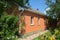 Cozy brick house with in beautiful green garden with climbing roses bush, trees and flowerbed