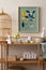 Cozy composition of easter living room interior with mock up poster frame, wooden sideboard, easter bunny, stylish bowl, colorful
