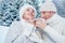 Cozy dressed couple in love drink hot of tea in winter forest