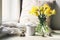 Cozy Easter, spring still life scene. Mug of coffee, wooden plate, quail eggs and vase of flowers on windowsill. Floral