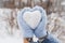 Cozy female hands in blue fluffy mitten with heart of snow