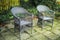 Cozy garden area for coffee and reading outside in the warm summer. Two grey woven lawn chairs on a stone patio outside