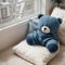 Cozy holidays at home. Cute little lying under blue knitted blanket with teddy bear on floor at window reading book. Winter season