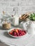 Cozy home breakfast served table - granola, milk, fresh raspberries and strawberries in the light kitchen. Flat lay