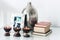 Cozy home interior decor, burning spa aroma candles in coconut shell, metal vase, pile of books, on white glass nightstand