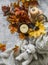 Cozy home still life - knitted blanket in a straw basket, pumpkin, bouquet of maple leaves, candle on a gray background, top view