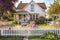 cozy house with warm and welcoming exterior, including a white picket fence and blooming flowers